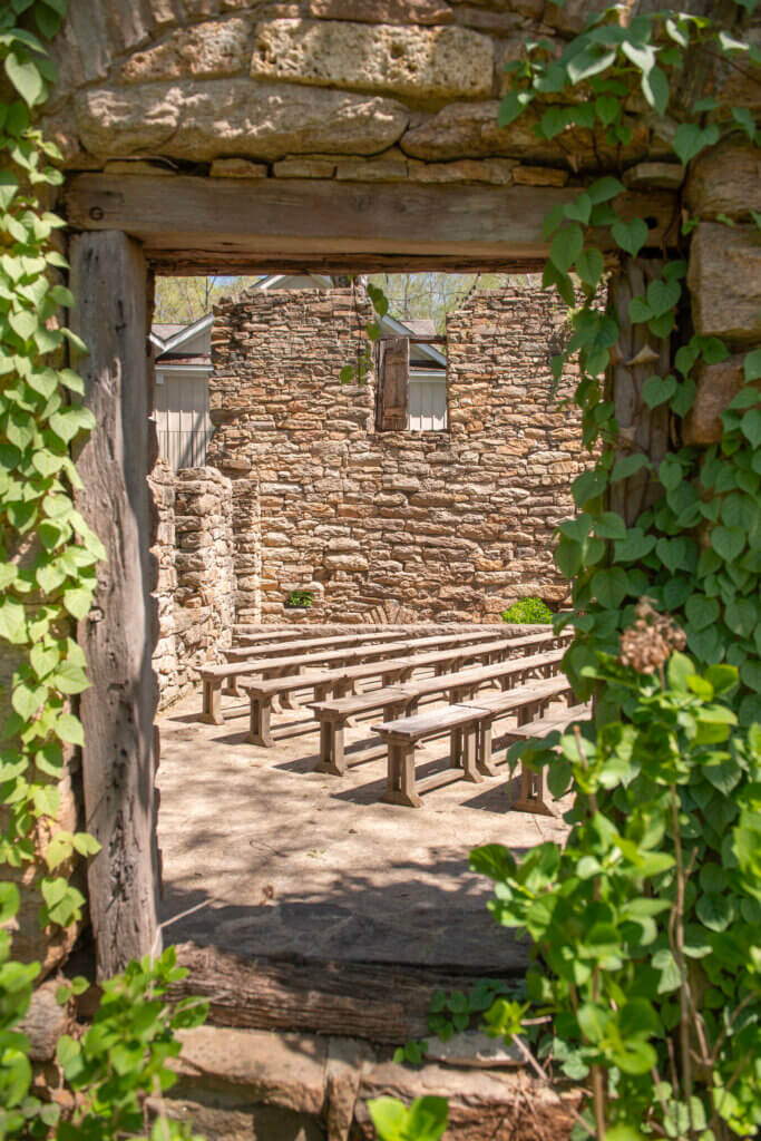 A peak through one of the windows of the Mill at Fine Creek ruins, showing the wood benches where guests enjoy a wedding ceremony